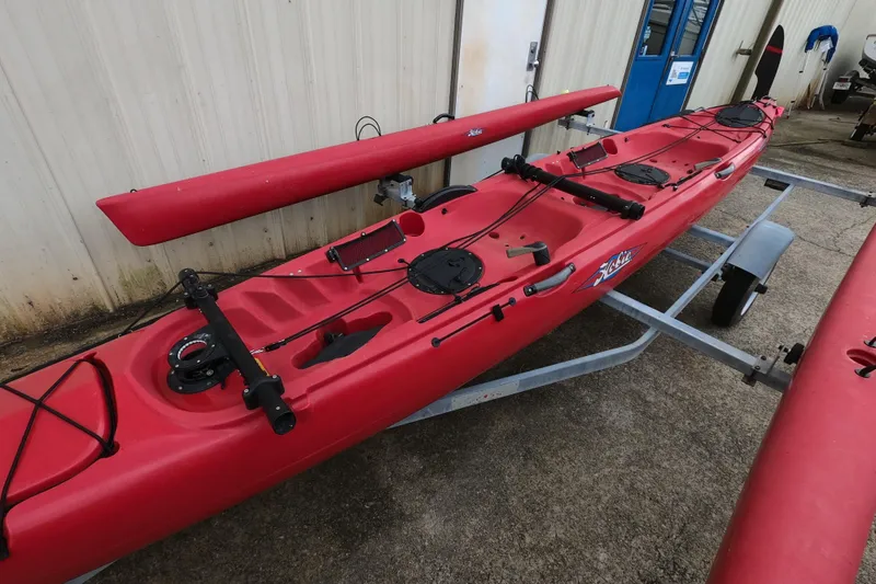 Slide: The Image of Red 2012 Hobie Mirage Tandem Island kayak on trailer, parked outdoors. - 2