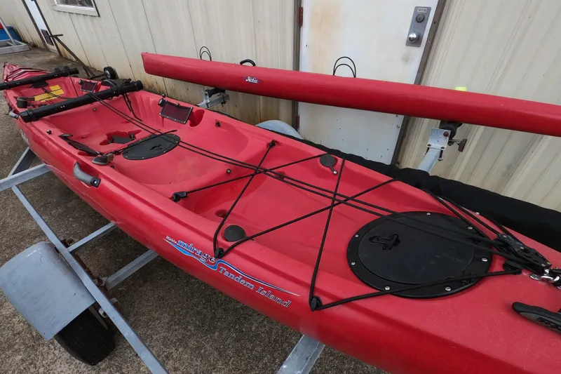 Slide: The Image of Red 2012 Hobie Mirage Tandem Island kayak on trailer, featuring storage hatches and rigging. - 5