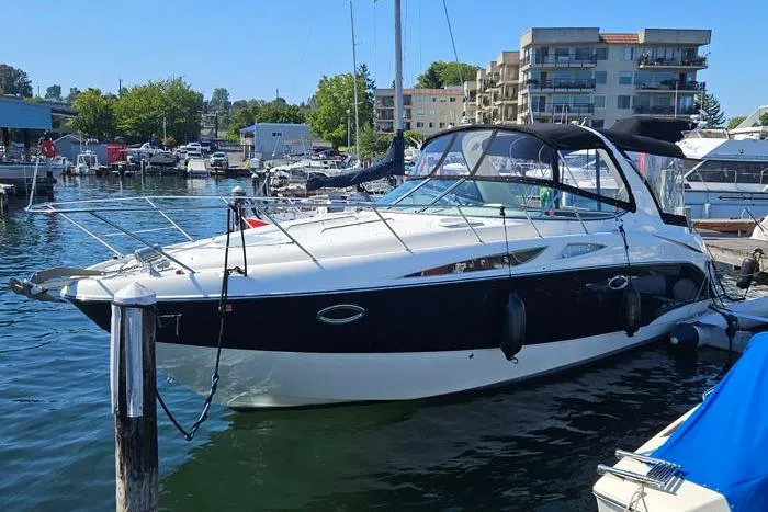 The Image of 2008 Bayliner 320 boat docked at a marina, surrounded by other boats and buildings. - 0