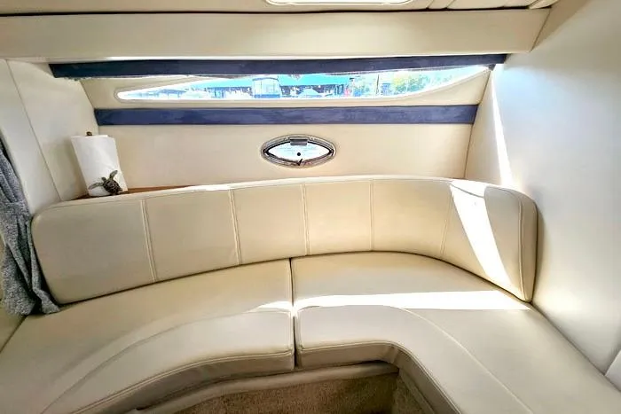 Slide: The Image of Interior of a 2008 Bayliner 320 boat with beige seating and a small window. - 13
