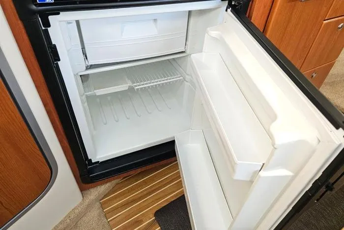 Slide: The Image of Open refrigerator inside a 2008 Bayliner 320 boat, showcasing storage shelves and compartments. - 16