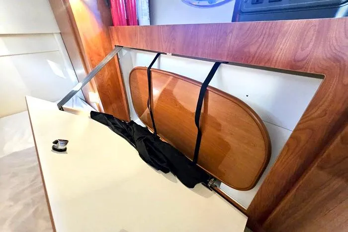 Slide: The Image of 2008 Bayliner 320 interior with foldable wooden table and storage compartment. - 18