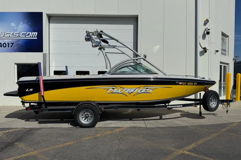 Slide: The Image of 2008 Moomba Mobius LS boat in yellow and black, parked on a trailer outside a building. - 0