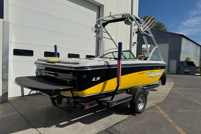 Slide: The Image of 2008 Moomba Mobius LS boat in yellow and black, parked outside a garage. - 1