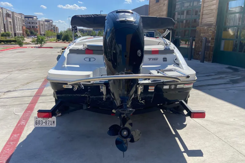 Slide: The Image of 2023 Tahoe T16 boat with outboard motor, parked in urban setting under clear sky. - 2