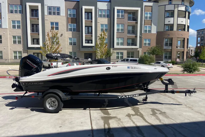Slide: The Image of 2023 Tahoe T16 boat on trailer, parked in urban setting with modern buildings. - 3