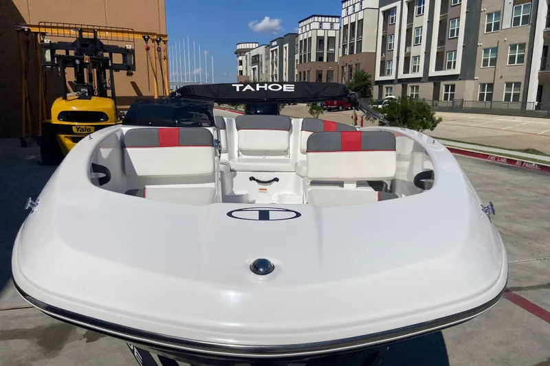 Slide: The Image of 2023 Tahoe T16 boat with white and red seating, parked near modern buildings. - 6