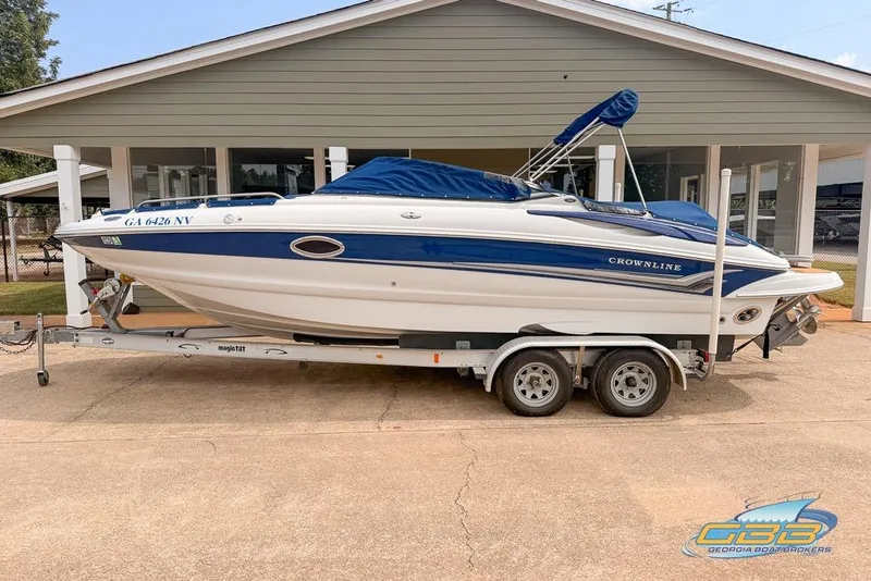 The Image of 2004 Crownline 240 EX boat on trailer, parked outside a building. - 0