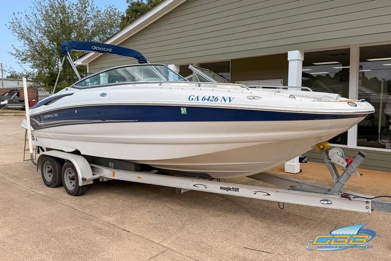 Slide: The Image of 2004 Crownline 240 EX boat on trailer, parked outside a building. - 2