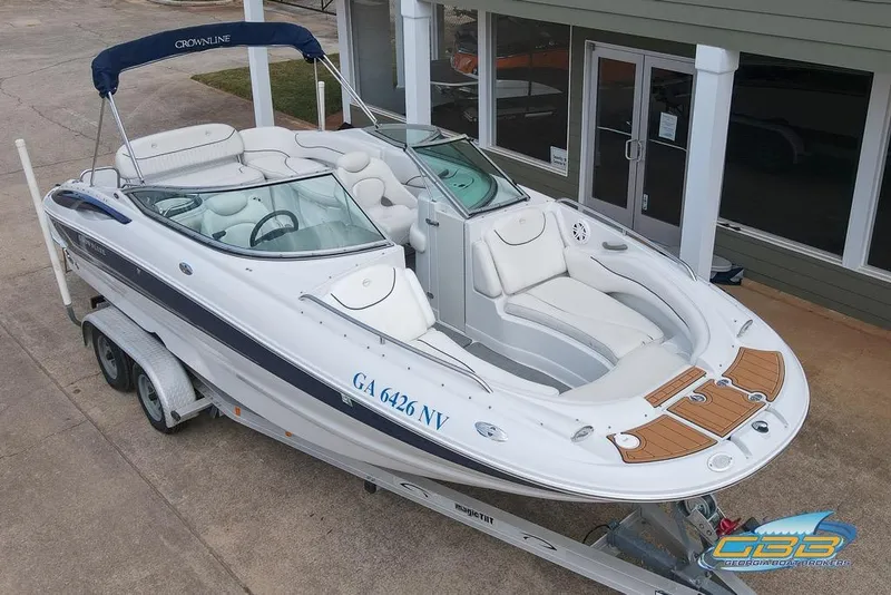Slide: The Image of 2004 Crownline 240 EX boat on trailer, white with blue accents, parked outside a building. - 3