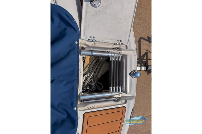 Slide: The Image of 2004 Crownline 240 EX boat with open storage compartment and blue cover. - 33