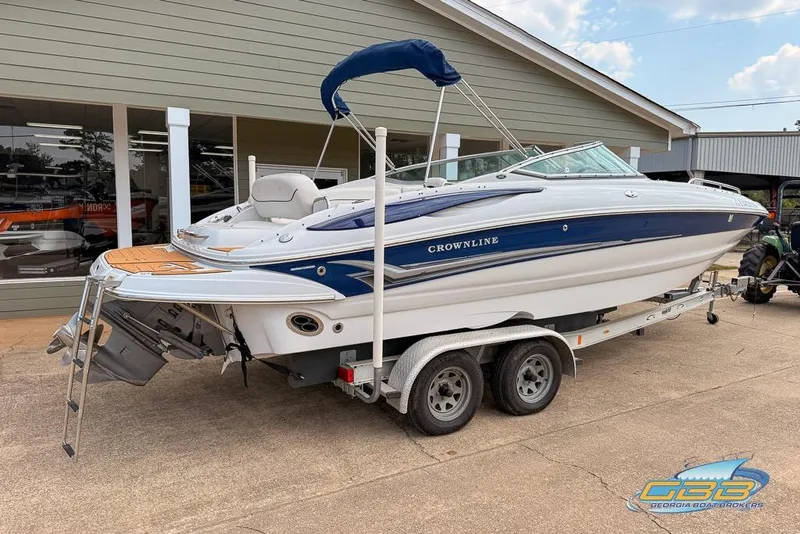 Slide: The Image of 2004 Crownline 240 EX boat on trailer, blue and white design, parked outside a building. - 8