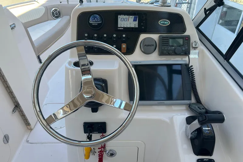 Slide: The Image of 2013 Grady-White Freedom 255 boat dashboard with steering wheel and navigation equipment. - 2