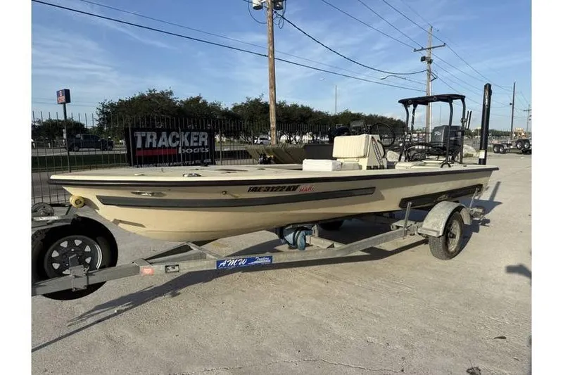 Slide: The Image of 2003 Buskens 17 Flats boat on trailer, parked outdoors near Tracker Boats sign. - 3