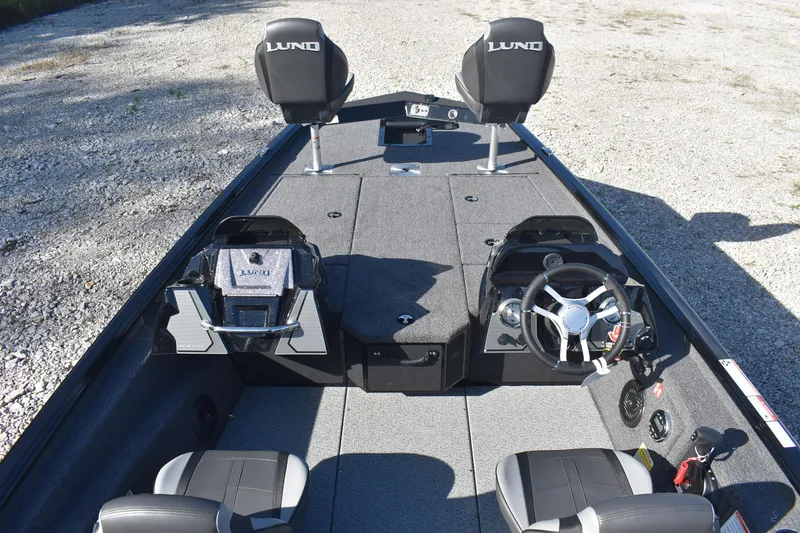 Slide: The Image of 2026 Lund 1875 Renegade boat deck with wiring and control panel on gravel surface. - 17