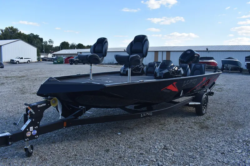 Slide: The Image of 2026 Lund 1875 Renegade boat on trailer, parked outdoors, featuring sleek design and modern seating. - 2