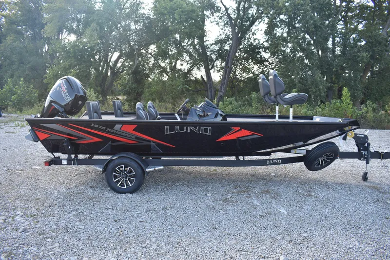 Slide: The Image of 2026 Lund 1875 Renegade boat on trailer, black with red accents, parked outdoors. - 5