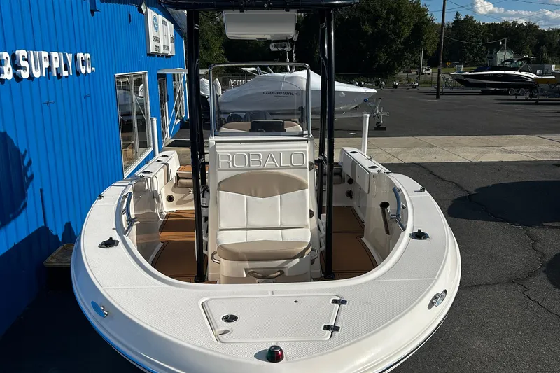 Slide: The Image of 2018 Robalo R180 Center Console boat displayed outdoors near a blue building. - 5