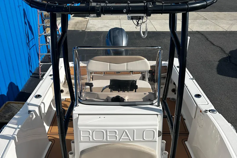 Slide: The Image of 2018 Robalo R180 Center Console boat with steering wheel and seating, docked near a blue building. - 7