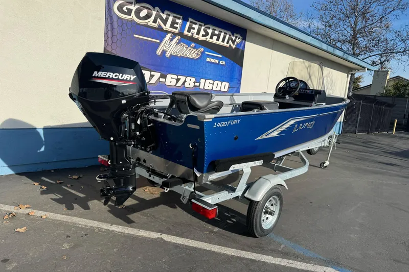Slide: The Image of 2026 Lund 1400 Fury SS boat with Mercury engine on trailer, parked outside dealership. - 4