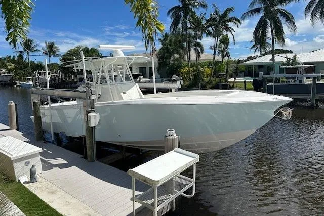 Slide: The Image of 2024 SeaVee 340Z boat docked by palm trees in a sunny canal setting. - 0