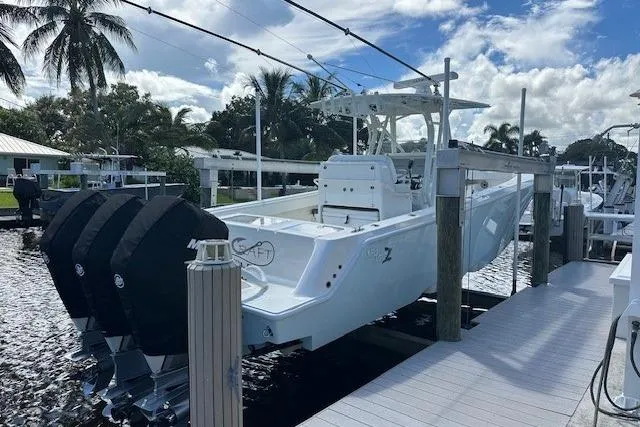 Slide: The Image of 2024 SeaVee 340Z boat docked, featuring triple outboard engines, under a partly cloudy sky. - 1