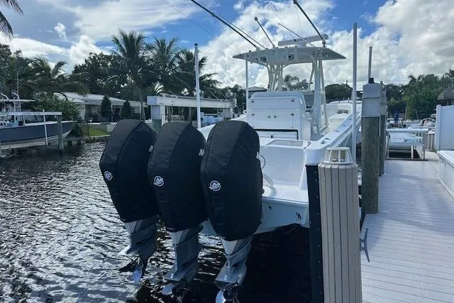 Slide: The Image of 2024 SeaVee 340Z boat docked, featuring triple outboard engines, under a partly cloudy sky. - 8