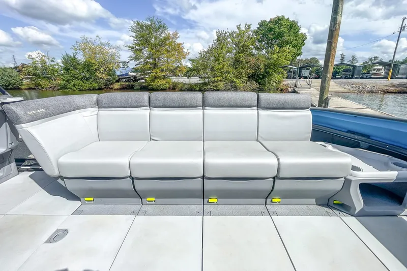 Slide: The Image of 2023 Sea-Doo Switch Cruise 21 boat seating, featuring gray cushioned seats and a scenic waterfront backdrop. - 14
