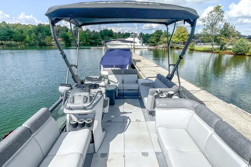 Slide: The Image of 2023 Sea-Doo Switch Cruise 21 pontoon boat docked on a scenic lake. - 15