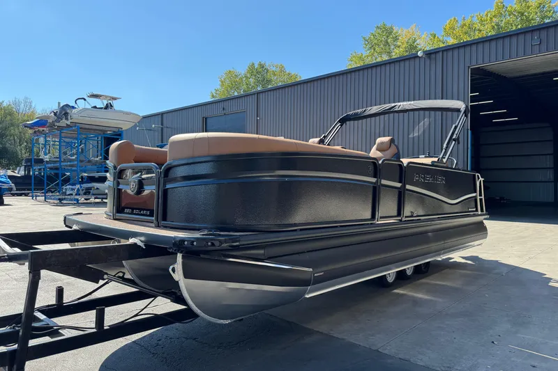 Slide: The Image of 2026 Premier 230 Solaris RL pontoon boat on trailer outside a warehouse. - 2