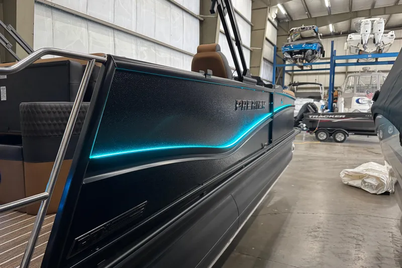 Slide: The Image of 2026 Premier 230 Solaris RL pontoon boat with sleek design and illuminated accents in a showroom. - 24