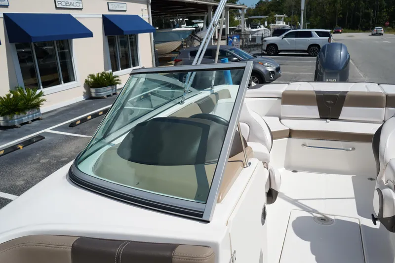 Slide: The Image of 2020 Chaparral 23 SSi OB boat interior with seating and windshield, parked near dealership. - 30