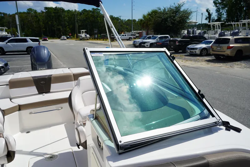 Slide: The Image of 2020 Chaparral 23 SSi OB boat interior with windshield and seating, parked outdoors. - 31