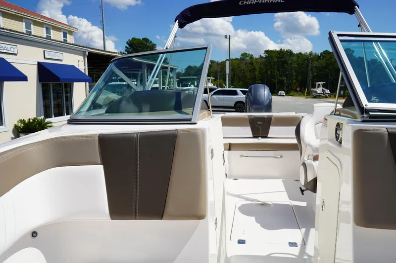 Slide: The Image of 2020 Chaparral 23 SSi OB boat interior with seating and windshield, parked outdoors. - 33