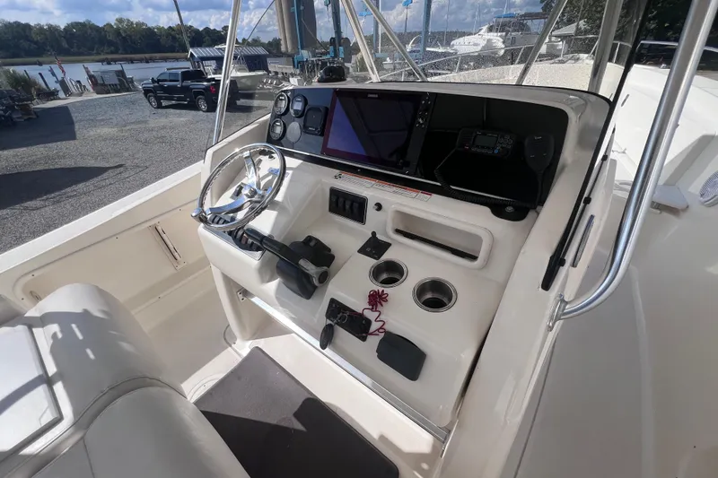 Slide: The Image of 2007 Pursuit C 300 Center Console boat on calm water, surrounded by lush greenery. - 6