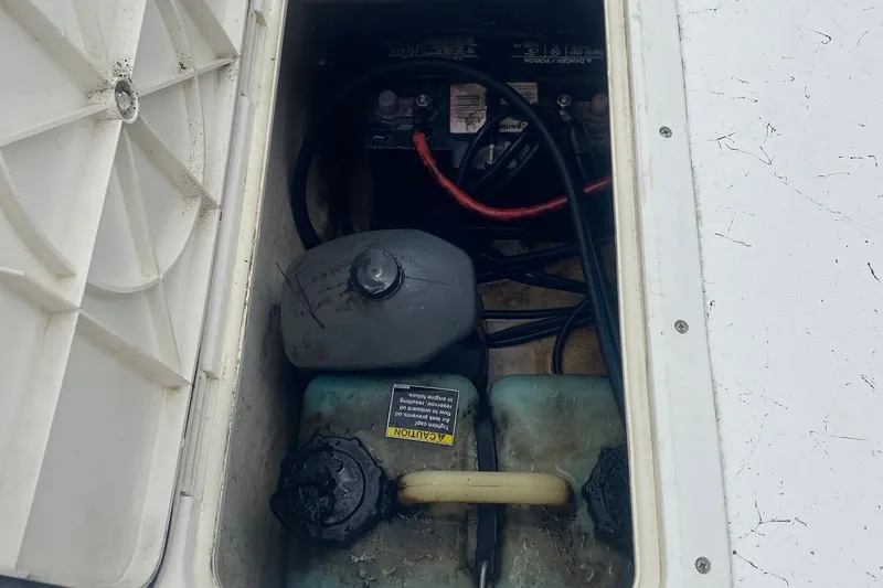 Slide: The Image of 2006 Mako 191 Inshore boat battery compartment with cables and fluid container. - 7