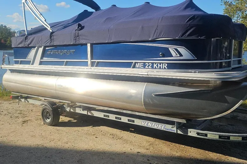 Slide: The Image of 2019 Starcraft EX 20 C pontoon boat on trailer, covered with navy tarp. - 0