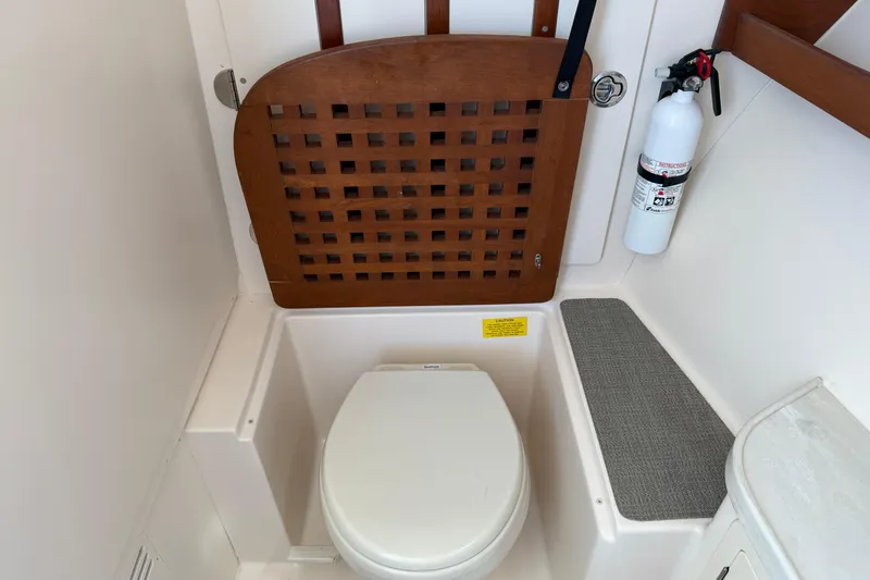 Slide: The Image of 2017 Grady-White Freedom 335 boat bathroom with toilet, wooden seat cover, and fire extinguisher. - 43