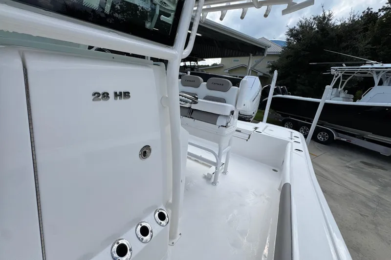 Slide: The Image of 2026 Caymas 28 HB boat interior with seating and console, parked outdoors. - 26
