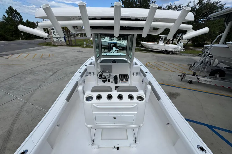 Slide: The Image of 2026 Caymas 28 HB boat interior with console and rod holders, parked on concrete. - 38