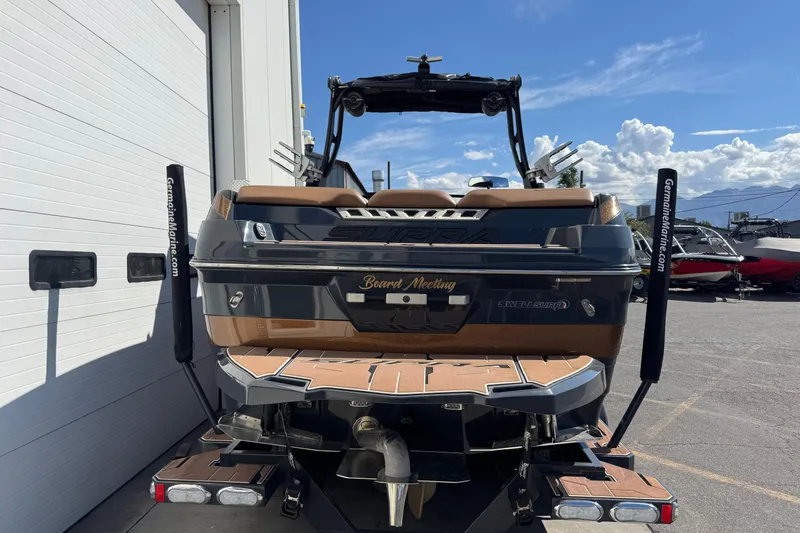 Slide: The Image of 2021 Supra SE 575 boat, rear view, parked outdoors under a clear blue sky. - 2