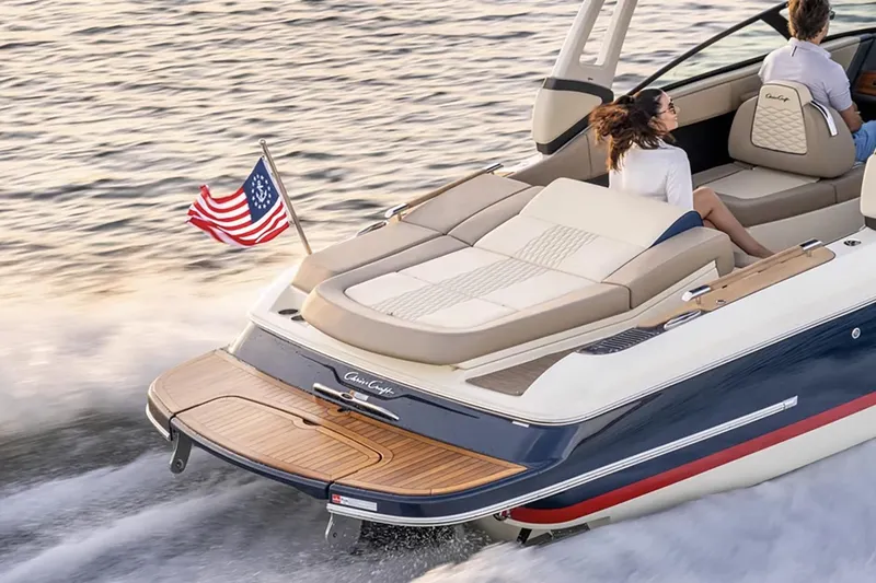 Slide: The Image of 2026 Chris-Craft Sportster 25 boat displayed indoors with American flag. - 3