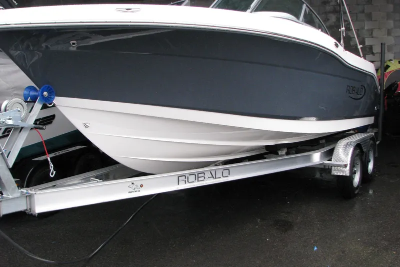 Slide: The Image of 2026 Robalo R207 Dual Console boat on trailer, sleek design, parked indoors. - 15