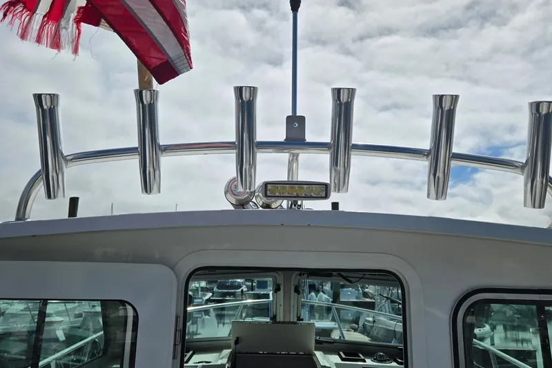 Slide: The Image of 2022 Parker 2520 XLD Sport Cabin boat with rod holders and American flag. - 3