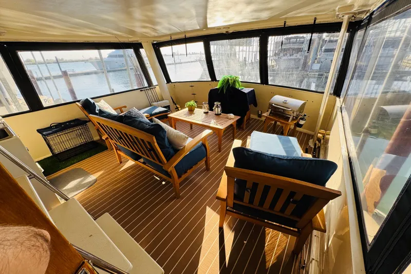 Slide: The Image of 1986 Californian 48 Motor Yacht interior with wooden furniture, cushions, and marina view. - 14