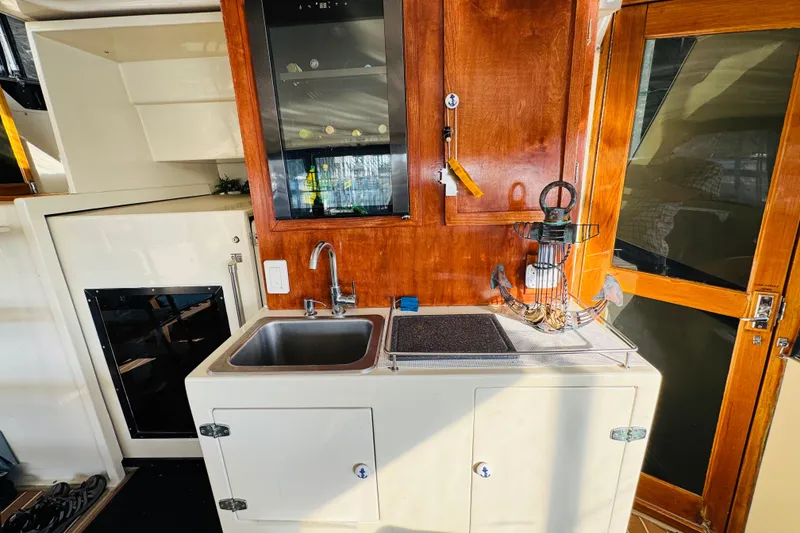 Slide: The Image of 1986 Californian 48 Motor Yacht kitchen area with sink, wooden cabinets, and nautical decor. - 21