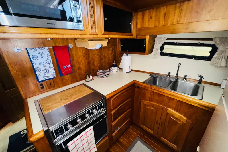 Slide: The Image of 1986 Californian 48 Motor Yacht kitchen with wooden cabinetry, stainless steel sink, and stove. - 49