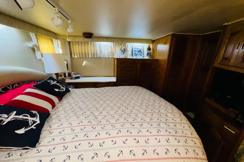 Slide: The Image of 1986 Californian 48 Motor Yacht bedroom with nautical-themed bedding and wooden cabinetry. - 57