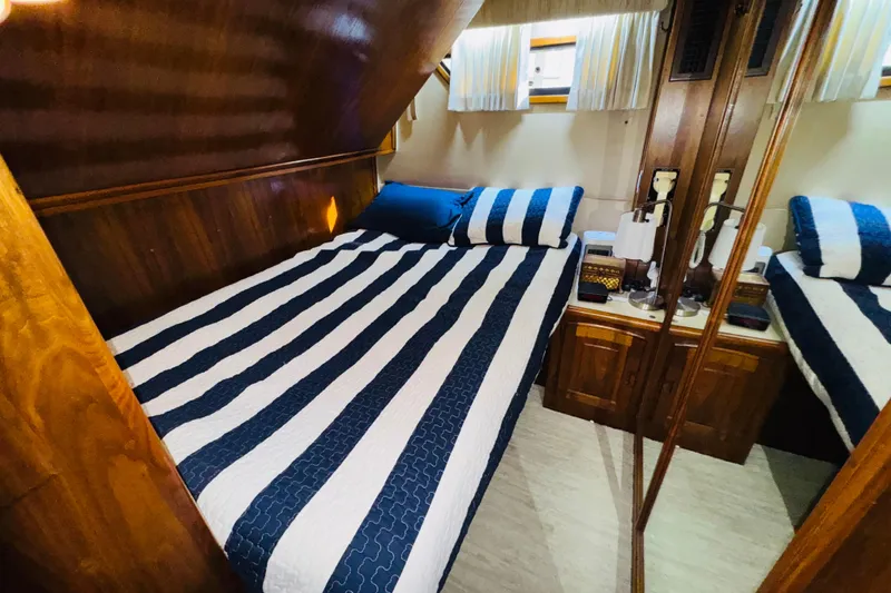 Slide: The Image of 1986 Californian 48 Motor Yacht bedroom with striped bedding and wooden interior. - 62