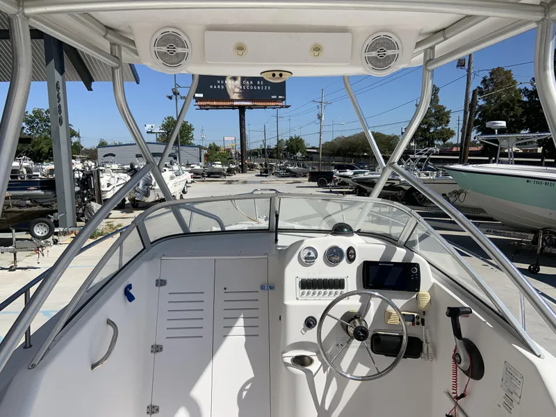 Slide: The Image of 2007 Pro-Line 21 Walk boat dashboard with steering wheel and controls in a marina setting. - 20